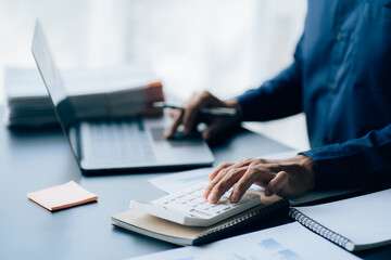 The hands of a male businessman are analyzing and calculating the annual income and expenses in a financial graph that shows results To summarize balances overall in office