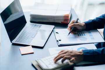 The hands of a male businessman are analyzing and calculating the annual income and expenses in a...