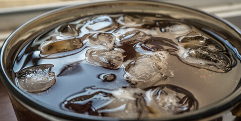 pieces of ice on the surface of the water in a mug close-up