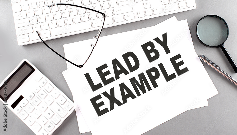 Poster lead by example text on paper with keyboard, calculator on grey background