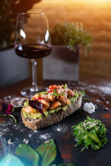 wine glass and fresh sandwich with avocado, red salmon fried fish, seaweed