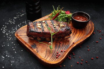 Grilled pork ribs with barbecue sauce and caramelized with arugula. Tasty beer appetizer on a...