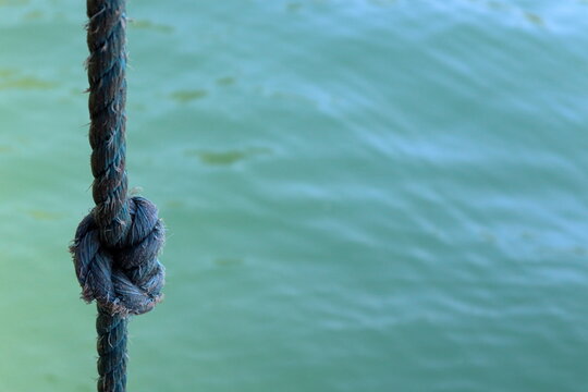 Rope with knot against the background of the green ocean sea water at Ubatuba, SP, Brazil.
