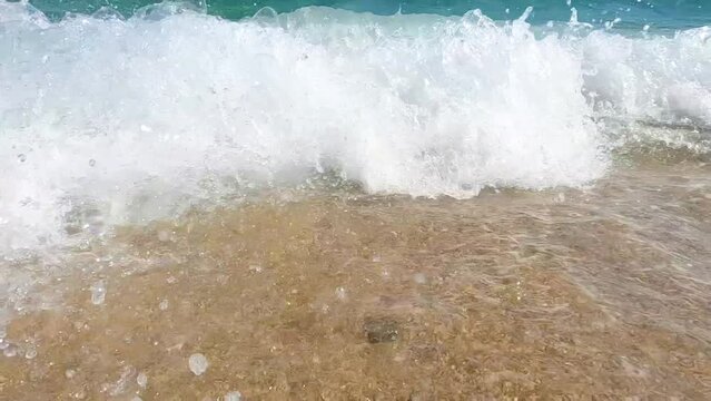 Sea waves splashing sandy beach on summer day. 4k slow motion