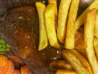 full frame food background of British steak pie served with chips. Traditional English pub food meal.