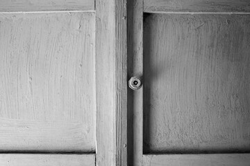 Vintage shabby cabinet with handle texture. White doors of an old wardrobe background black and white.Old abandoned wardrobe doors.