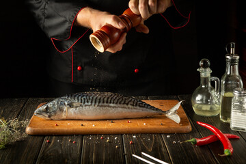 Fish chef prepares fresh mackerel in the kitchen. Scomber must be added with aromatic pepper before...