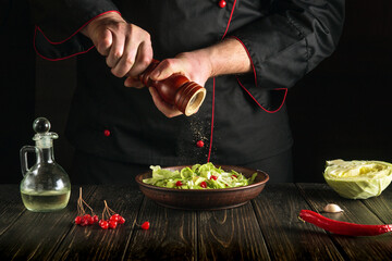 The chef adds hot peppers to a salad of fresh vegetables and cabbage. Vegetarian cuisine or diet