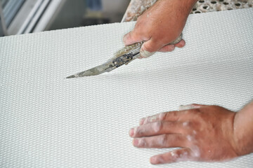 Man cutting polystyrene foam heat insulation with old retractable utility knife, closeup detail
