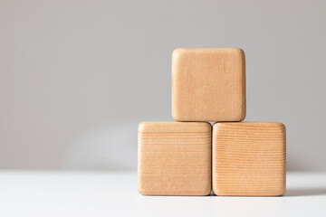 Stacked wooden blocks form a pyramid staircase on a white tabletop with a gray background.Concept of success, growth, victory, foundation work, strength, development or top ranking.Free space for text