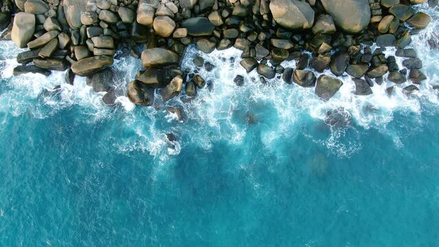 Aerial view top down waves texture breaking rock stones sea background. 