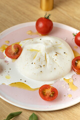 Buratta cheese and tomatoes in a bowl. fresh soft white burrata cheese ball made from mozzarella and cream from Apulia, Italian Mediterranean cuisine, vertical image.