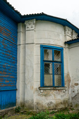 An old dilapidated wooden building with columns and a concrete extension. Restoration of a historic building.