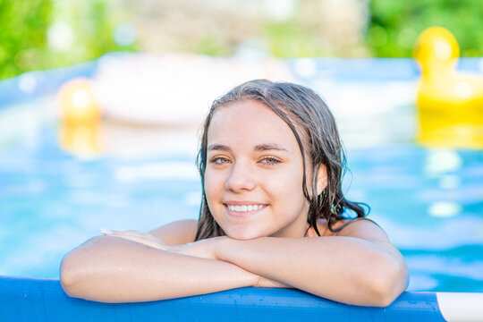 Smiling teen girl enjoing in the pool at sunny day