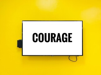  courage note on television against yellow wall