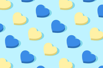 Fashionable pattern in alternation of blue and yellow. Geometric hearts in the pastel colors of the Ukrainian flag. Minimal holiday concept. Solar shadow.