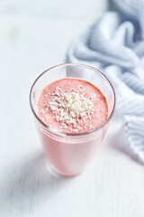Obraz na płótnie Canvas Glass of strawberry-banana smoothie made with yoghurt and coconut