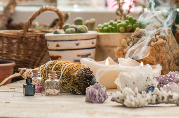 Cozy space with candles, crystals, herbs, and plants. Alternative medicine, herbal medicine, aromatherapy or esoteric background with incense smoke.