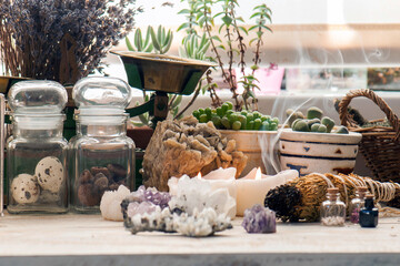 Cozy space with candles, crystals, herbs, and plants. Alternative medicine, herbal medicine, aromatherapy or esoteric background with incense smoke.