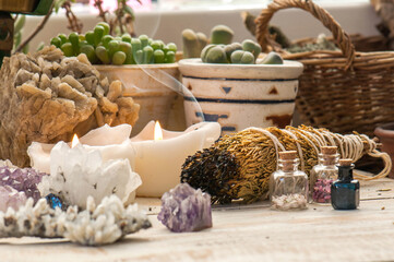 Cozy space with candles, crystals, herbs, and plants. Alternative medicine, herbal medicine, aromatherapy or esoteric background with incense smoke.