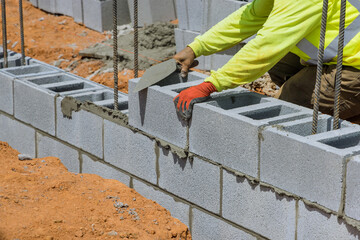 This mason installing a wall of aerated concrete blocks around him on construction site