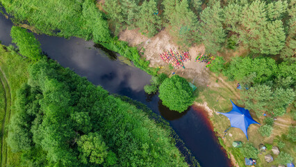 Aerial view of camping with kayaks on the beach of river on a sunny day. Modern kayaks with paddles on beach near river.