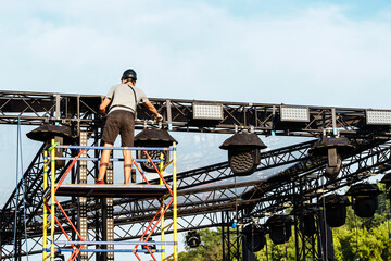 Installation of lighting equipment on a mobile concert stage. A worker installs spotlights under a...