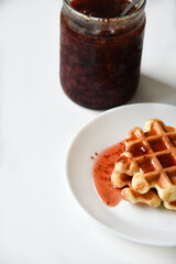 Viennese waffles with jam on a white plate. Delicious sweet breakfast with waffle.
