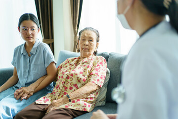 Asian young woman taking her mother to see an orthopedic doctor at hospital.