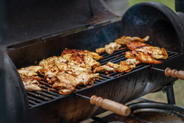 BBQ quail grilled over an open fire. Grilled meat on a charcoal grill. Picnic in the backyard during a family holiday. Barbecue meat.