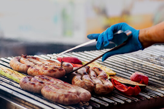 BBQ sausages are grilled over an open fire. Grilled sausages on a charcoal grill. Picnic in the backyard during a family holiday. BBQ food