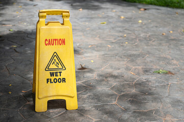 Caution wet floor" warning sign with people slipping icon, placed on marble wet floor during service by janitor. Sign and symbol object photo. Selective focus.