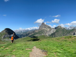 Fototapeta na wymiar father and son walk through a high mountain meadow with the Pic du Midi d'Ossau in the background