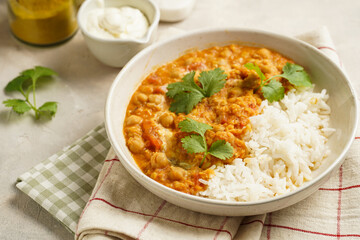 Indian red lentil curry with chickpeas, white rice and fresh cilantro - chana dal - in a white bowl on a green checkered kitchen towel - obrazy, fototapety, plakaty