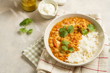Indian red lentil curry with chickpeas, white rice and fresh cilantro - chana dal - in a white bowl on a green checkered kitchen towel - obrazy, fototapety, plakaty