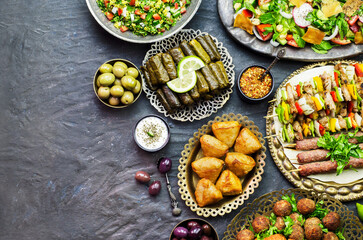 Arabic cuisine;Assorted of middle eastern traditional dishes. Stuffed vine leaves,olives, kibbeh, shish tawook, flafel, sambusak, tabbouleh and fattoush salad. Halal food. Top view with copy space.