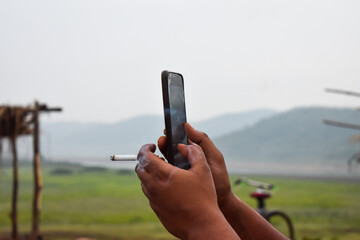Man holding cigarette and mobile in his hand