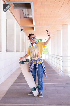 Smiling teenage skateboarder boy taking a picture of himself with his skateboard. Freestyle concept. Space for text.