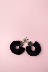 Handcuffs for sex games on pink background. Sexual bdsm toy. Erotic concept. Vertical photo