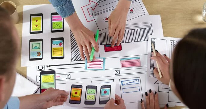 Web designers are developing a smartphone interface. Engineers create sketches of applications for mobile phones. User experience concept.