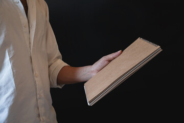 man in a white shirt holding brown notebook