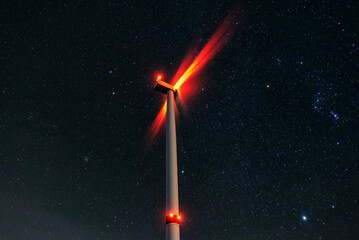 Night photo of a windmill and stars with abstract lighting. Wind turbine at night against the...