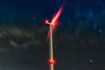 Night photo of a windmill and stars with abstract lighting. Wind turbine at night against the background of stars. Environment and Renewable Energy