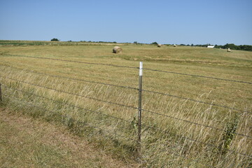 Barbed Wire Fence and Hay Bales in a Farm Field