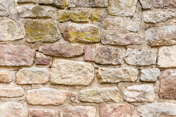 Wand oder Mauer aus Sandstein Ziegeln mit rissigen Fugen und Moos