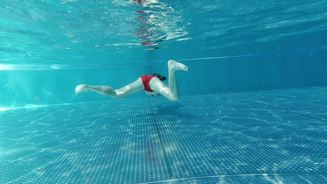 Little girl practice swim and dive underwater in swimming pool at summer