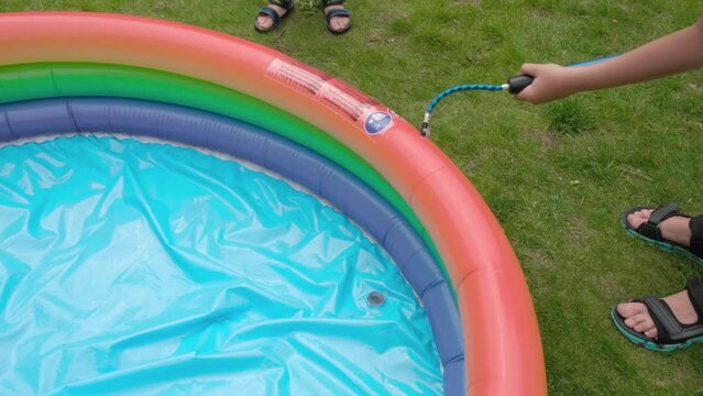 Children inflate a small pool with a pump. The idea of recreation in the yard, in nature. High quality 4k footage
