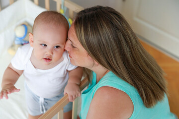 Baby boy standing in cot.