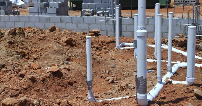Under the foundation of a new residential construction home, sewer pipes and water pipes are buried in the ground an aerial view