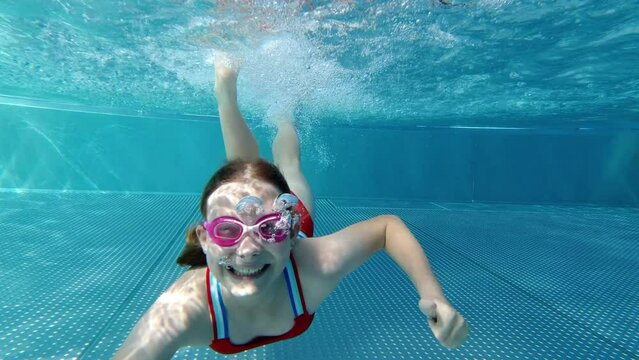 Happy cute child joyfully diving and playing in swimming pool